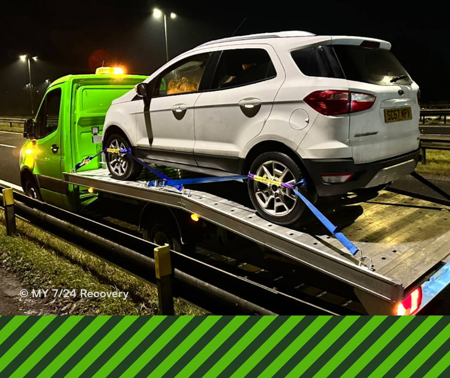 Recovery operator securing a car on a flatbed truck